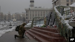 Un militar ucraniano se arrodilla frente a un monumento dedicado a las personas que murieron en enfrentamientos con las fuerzas de seguridad, en la Plaza Independiente (Maidan) en Kiev, Ucrania, el lunes 21 de noviembre de 2022.