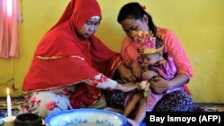 Seorang balita perempuan duduk di pangkuan ibunya dalam upacara sunat di Gorontalo, Provinsi Gorontalo, 20 Februari 2017. (Foto: Bay Ismoyo/AFP)