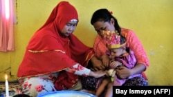 Seorang balita perempuan duduk di pangkuan ibunya dalam upacara sunat di Gorontalo, Provinsi Gorontalo, 20 Februari 2017. (Foto: Bay Ismoyo/AFP)