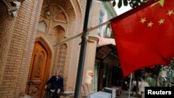 Seorang pria tampak di belakang bendera China di Kota Tua di Kashgar di
Wilayah Autonomi Xinjiang Uighur, China, 6 September 2018. (Foto: Reuters)