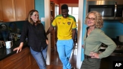 Cabrel Ngounou, center, a refugee from Cameroon, talks with his sponsors, Lori Ostlund, left, and Anne Raeff, in their home in San Francisco on Sept. 17, 2024.