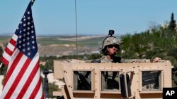 FILE - A U.S. soldier sits in his armored vehicle on a road leading to the front line in Manbij, Syria, April 4, 2018.