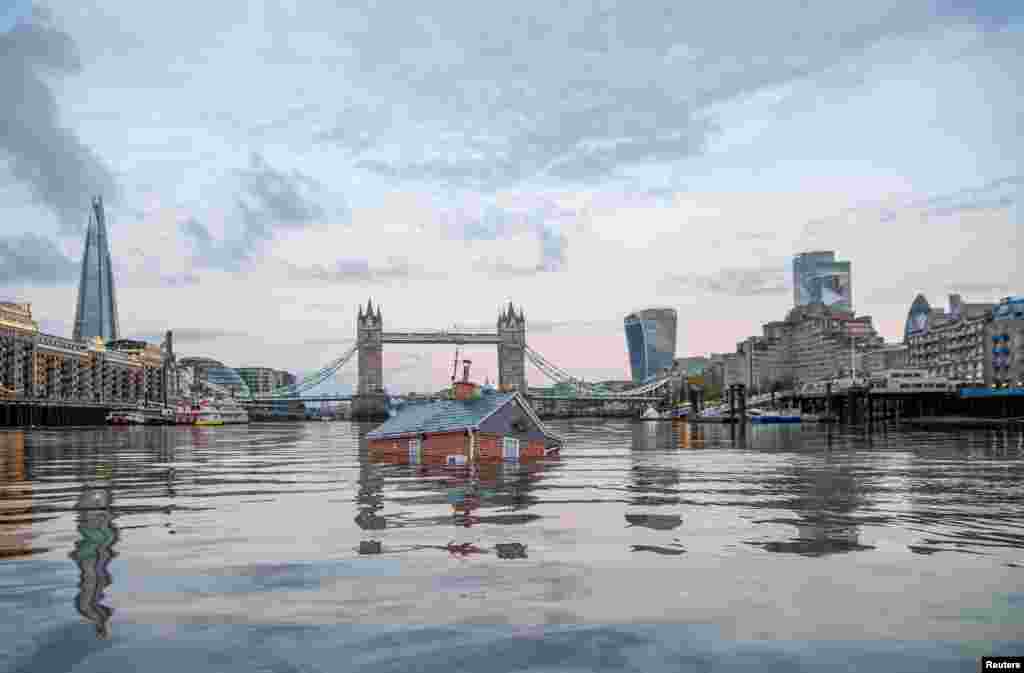 A mock-up of a typical British suburban home is seen sinking into the River Thames, in a protest by Extinction Rebellion to demand faster government action on climate change in London. (Extinction Rebellion/Guy Reece/Handout)