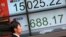 People walk past an electronic stock board showing Japan's Nikkei 225 in Tokyo, Friday, Feb. 12, 2016.