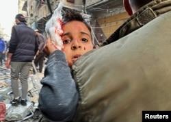 A Palestinian carries a wounded child at the site of an Israeli strike on an apartment building in Nuseirat, Gaza Strip, on Dec. 20, 2024.