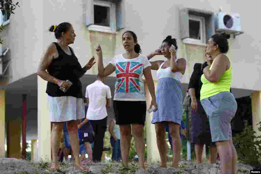 Israeli onlookers stand at the scene after a rocket landed in the southern coastal city of Ashkelon, Aug. 26, 2014.