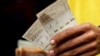 El asistente de un conductor de autobús sostiene billetes de 200.000 bolívares, en Caracas. Marzo 16, 2021.