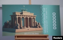 FILE - A print of Germany’s first crypto postage stamp worth 1.60 Euro showing the artificial intelligence (AI) interpretation of the Brandenburg Gate stands on an easel during its presentation in Berlin, Germany, October 25, 2023.