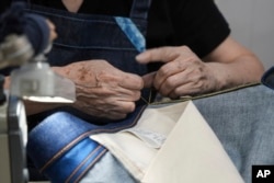 Naomi Takebayashi, a seamstress at Momotaro Jeans, hand-stiches a pair of jeans in Kojima, Okayama prefecture, western Japan, on Sept. 4, 2024. (AP Photo/Ayaka McGill)