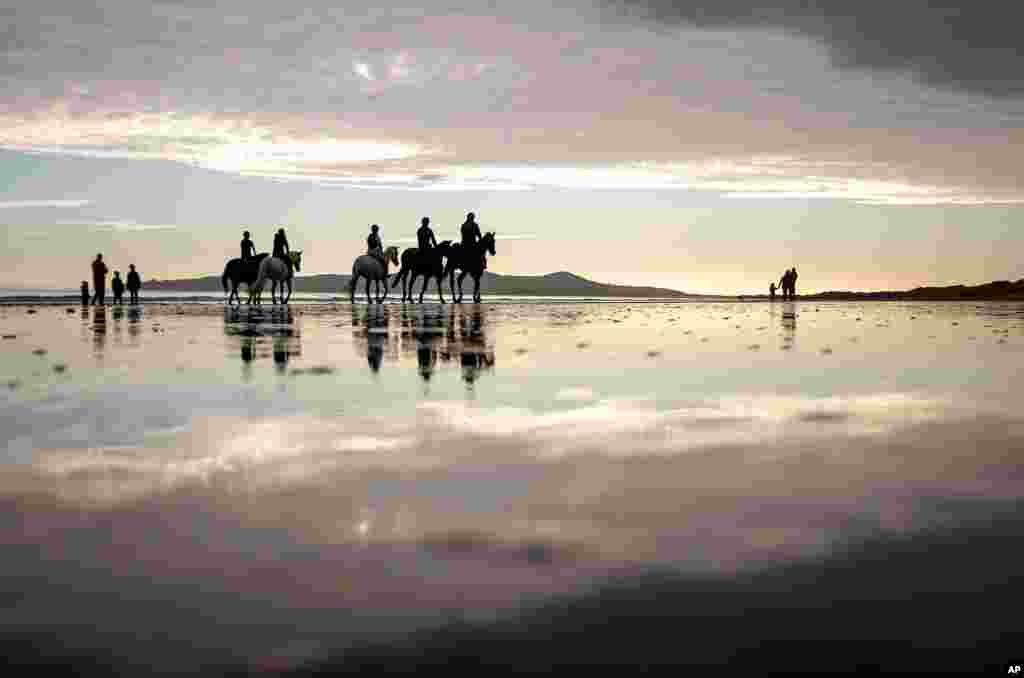 People ride horses along the beach in Portmarnock, County Dublin, Ireland.