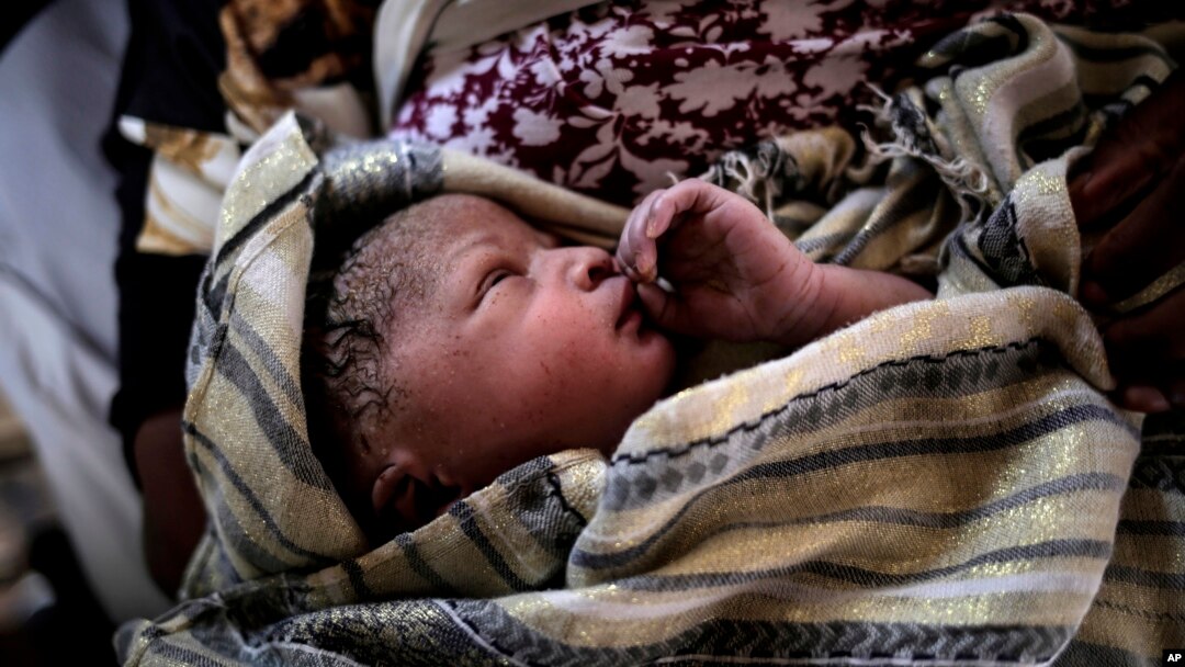 Seorang bayi perempuan yang baru lahir didekap ibunya, yang seorang perempuan migran asal Ghana. Sang ibu melahirkan segera setelah diselamatkan oleh kapal penyelamat Spanyol, di Laut Mediterania, 6 September 2017.
