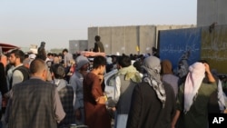 Hundreds of people gather near an evacuation control checkpoint during ongoing evacuations at Hamid Karzai International Airport, in Kabul, Afghanistan, Aug. 25, 2021.