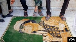 Los rebeldes libios usan de alfombra una imágen de Moammar Gadhafi, a la entrada del campamento en Tarhouna.