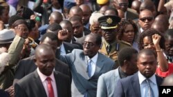 Le président zimbabwéen Robert Mugabe, au centre, salue de la main après s'être adressé aux membres de l'Association des anciens combattants de la guerre de libération nationale du Zimbabwe, au siège du parti, Harare, 27 juillet 2016.