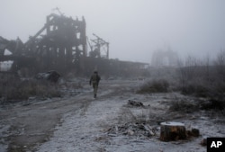 FILE - A Ukrainian soldier passes by a destroyed Butovka coal mine as he approaches a frontline position in the town of Avdiivka in the Donetsk region, Nov. 9, 2019.