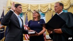 Mark Esper, left, is sworn in as Secretary of Defense by Supreme Court Justice Samuel Alito, right, as his wife Leah Esper holds the Bible, during a ceremony with President Donald Trump in the Oval Office at the White House in Washington, July 23, 2019.