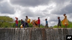 FILE—Children fill cans with water from a sand dam in Makueni County, Kenya, on Friday, March 1, 2024.