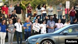 Local residents show their support as students arrive at Marjory Stoneman Douglas High School for the first time since the mass shooting in Parkland, Florida, Feb. 28, 2018. 