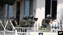 Polisi San Diego Police bersiap memasuki rumah tersangka penembakan di kota itu (29/7). (AP/Denis Poroy)