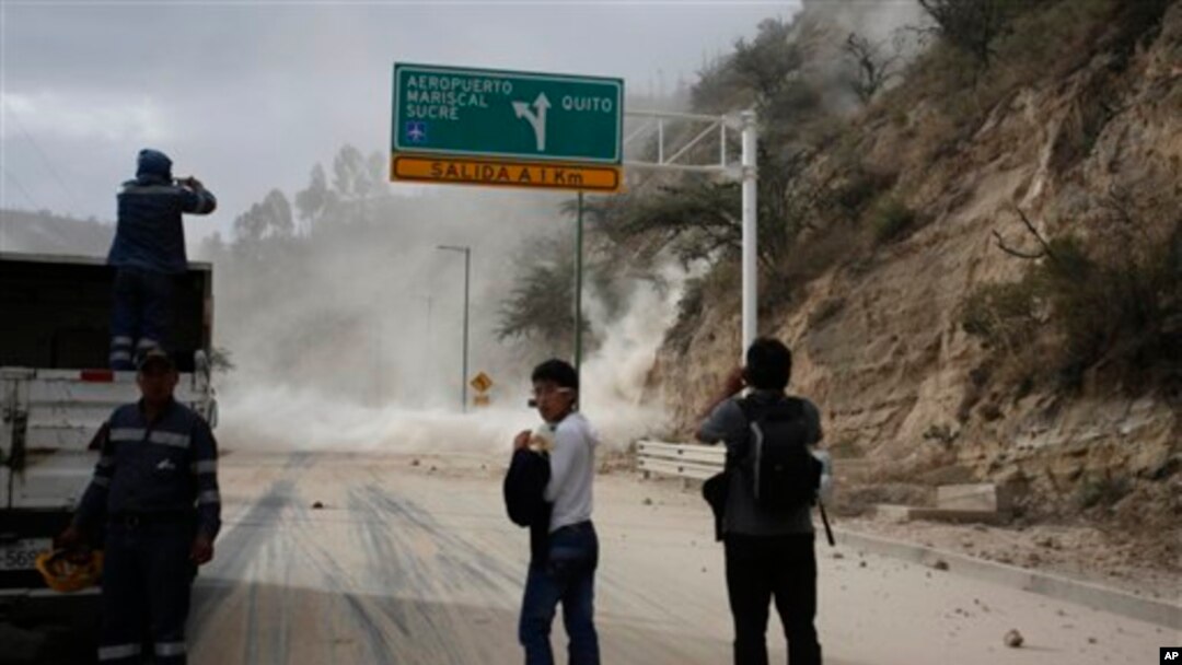 People watch as earth, dust spill on the Pan-American highway as result of an earthquake, north of Quito, Ecuador, Aug. 12, 2014.