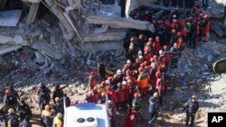 터키 동부 엘라지에서 규모 6.8의 지진이 발생한 후 구조대원들이 26일 붕괴된 건물들 사이로 실종자 수색작업을 하고 있다. 