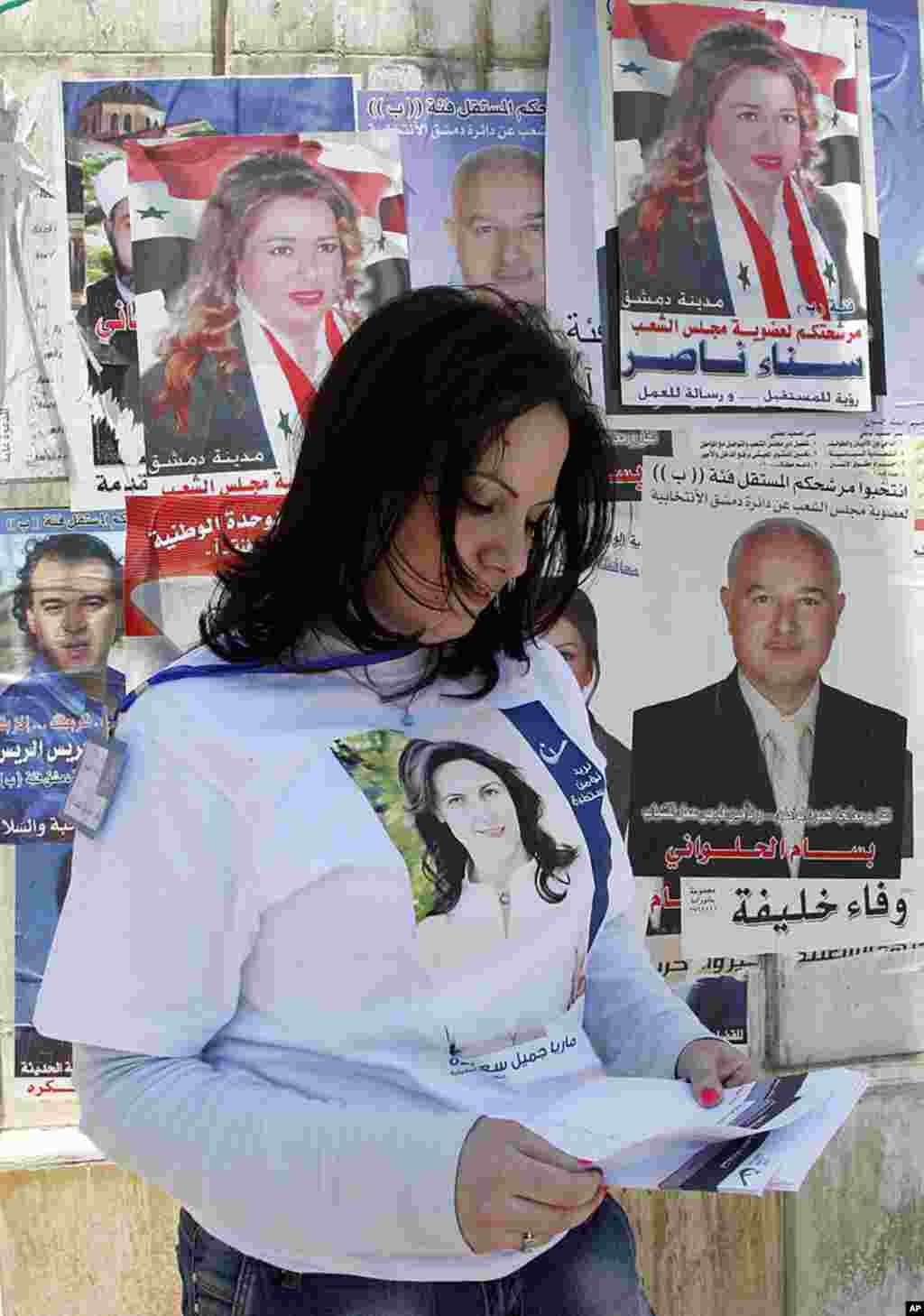 A woman wearing a T-shirt with a picture of a candidate in the parliamentary elections, stands in front of a polling center. (Reuters)
