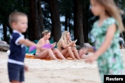 Russian tourists sit at the beach in Phuket, Thailand