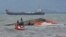 Rescuers tie a rope at the capsized vessel MBCA Kim-Nirvana to pull it towards the shore near a port in Ormoc city, central Philippines, July 3, 2015. 