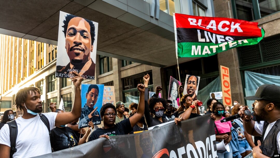 People raise their fists and hold signs and a banner as they march during an event in remembrance of George Floyd in Minneapolis, Minnesota, on May 23, 2021. 
