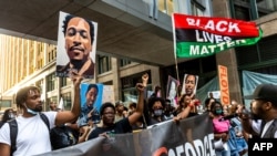 People raise their fists and hold signs and a banner as they march during an event in remembrance of George Floyd in Minneapolis, Minnesota, on May 23, 2021. 