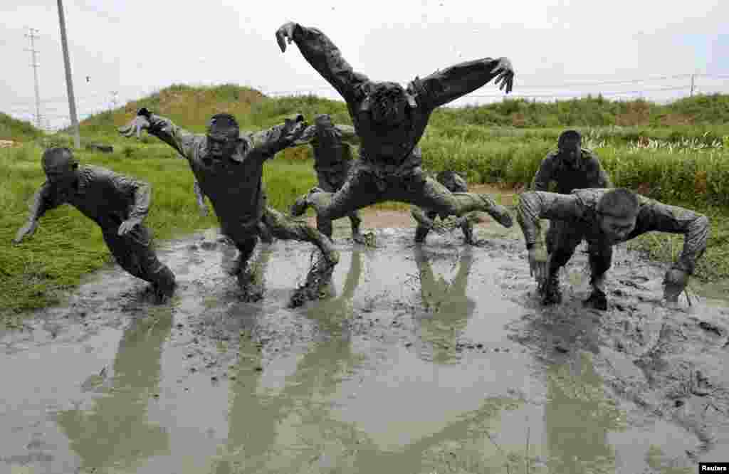 Paramilitary policemen jump during a training session in muddy water at a military base in Chuzhou, Anhui province, China.
