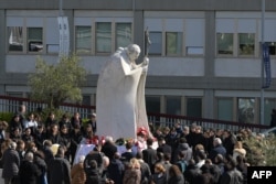 People gather to pray at the statue of John Paul II outside the Gemelli University Hospital where Pope Francis is hospitalized with pneumonia, in Rome, Italy, March 02, 2025.