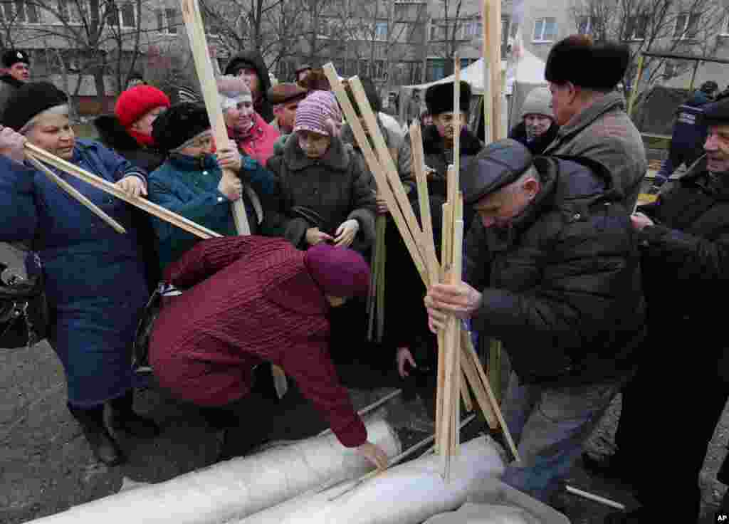 Residents collect materials to cover broken windows after Saturday's attack in Mariupol, Ukraine, Jan. 26, 2015. 