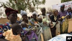 Women wait to receive baby food in the village of Koleram, southern Niger, during the launch of a UN-backed blanket feeding operation aimed at fighting malnutrition among children under the age of two, 28 Apr 2010