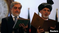 အာဖဂန်နစ္စတန်သမ္မတသစ် Ashraf Ghani (ယာ) နဲ့ အမှုဆောင်အရာရှိချုပ်သစ်Abdullah Abdullah တို့ ကျမ်းသစ္စာကျိန်ဆိုနေစဉ်။ (စက်တင်ဘာ ၂၉၊ ၂၀၁၄)