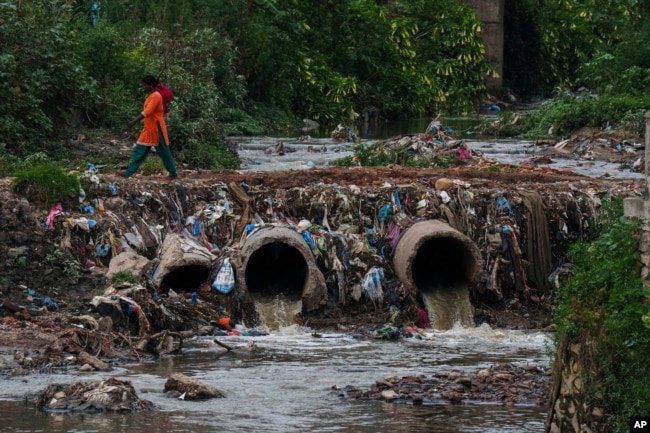 A woman walks over drainage pipes that flow into the Bagmati River in Kathmandu, Nepal, Wednesday, June 1, 2022. (AP Photo/Niranjan Shrestha)