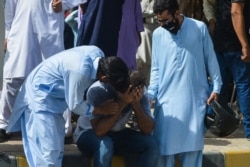 People comfort a relative of a victim near the site after a Pakistan International Airlines aircraft crashed in a residential area in Karachi, May 22, 2020.