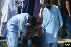 People comfort a relative of a victim near the site after a Pakistan International Airlines aircraft crashed in a residential area in Karachi, May 22, 2020.