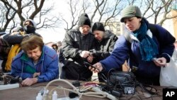 Orang-orang yang terkena badai Sandy di Long Beach, New York, mengisi ulang baterai smartphone mereka. (Foto: dok. AP/Kathy Kmonicek)