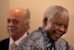 FILE - Former South African president Nelson Mandela walks past George Bizos as he leaves a media briefing after his acceptance of the historical collections from the National Archives at the Mandela foundation in Houghton, Nov. 28, 2008.