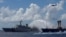 FILE - A Taiwan Coast Guard ship, left, extinguishes a fire on a cargo ship during a rescue drill near the coast of Itu Aba, which the Taiwanese call Taiping, at the South China Sea, Nov. 29, 2016.