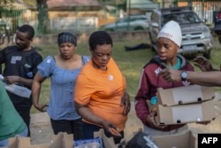 FILE - Survivors of the fire that ripped through the five-storey building in the early hours on August 31, 2023 killing 74 people, receive donated food at a provisional shelter in Johannesburg on September 1, 2023. (Photo by GUILLEM SARTORIO / AFP)
