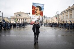 FILE - A supporter carries a portrait of former Soviet dictator Josef Stalin during a rally marking Defenders of the Fatherland Day, in Moscow, Russia, Feb. 23, 2020.