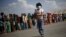 A displaced earthquake victim carries food and water after collecting them from a distribution center at an open ground, in Kathmandu, Nepal, May 4, 2015.