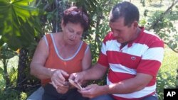 In this Friday, March 20, 2015 photo, Fidelia Rodriguez and her son Camilo hold old photos of U.S. citizen Daniel Smith and his family from before the Cuban Revolution in the Isle of Pines, Cuba.