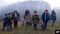 Two Afghan families walk in a clearing after leaving a Croatian forest near the Bosnian town of Velika Kladusa.