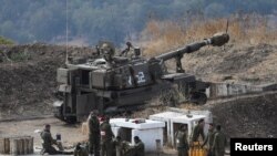 Israeli soldiers stand next to an artillery unit on the Israeli side of the border with Lebanon, August 6, 2021. 