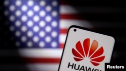 Foto ilustrasi yang menunjukkan sebuah ponsel pintar dengan logo Huawei pada layarnya berada di depan bendera AS. Foto diambil pada 28 September 2021. (Foto: Reuters/Dado Ruvic)