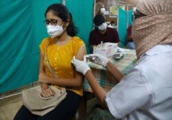 A health worker administers the Covishield, Serum Institute of India's version of the AstraZeneca vaccine, during a special vaccination drive for students traveling abroad, in Hyderabad, India, Friday, June 11, 2021. (AP Photo/Mahesh Kumar A.)