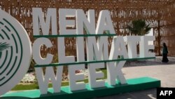 FILE - A woman walks past the entrance of the convention centre before the opening session of the Middle East and North Africa (MENA) Climate Week, a UN-organised conference hosted in the Saudi capital Riyadh, on October 8, 2023.